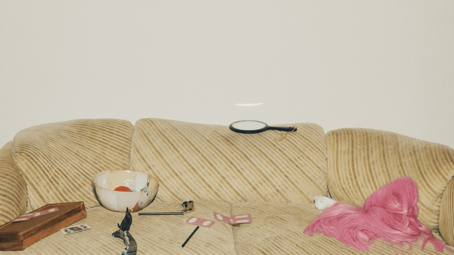 a messy sofa with a handheld mirror laying on a cushion